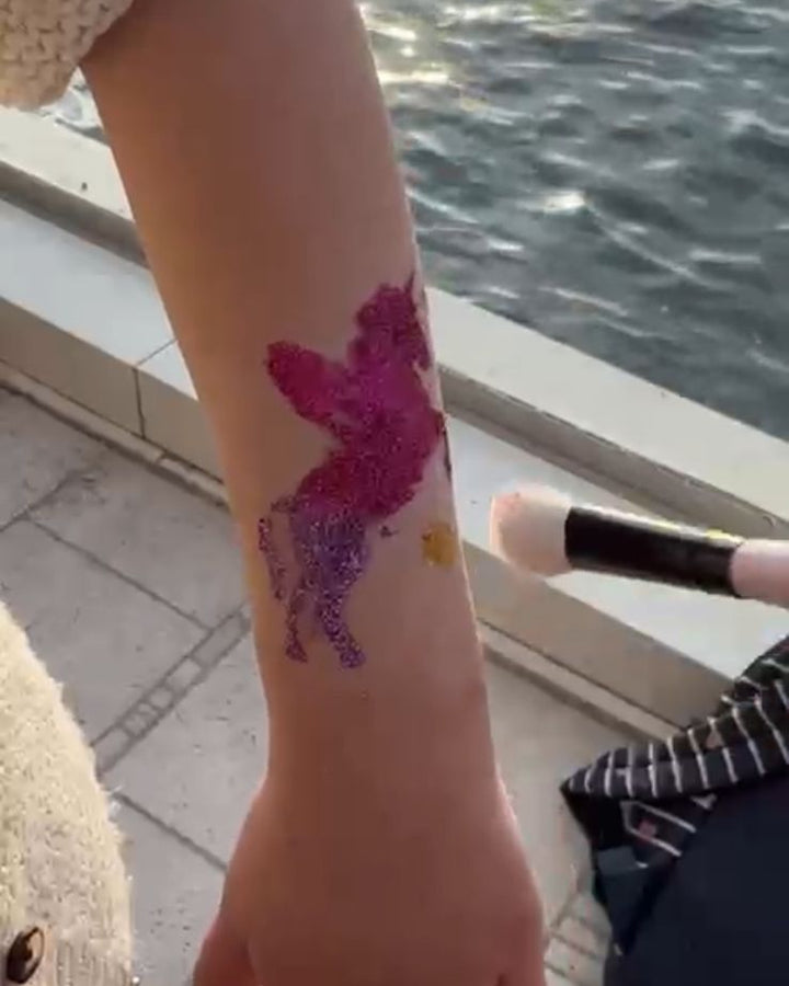 Child's arm with a pink deer tattoo by a waterfront